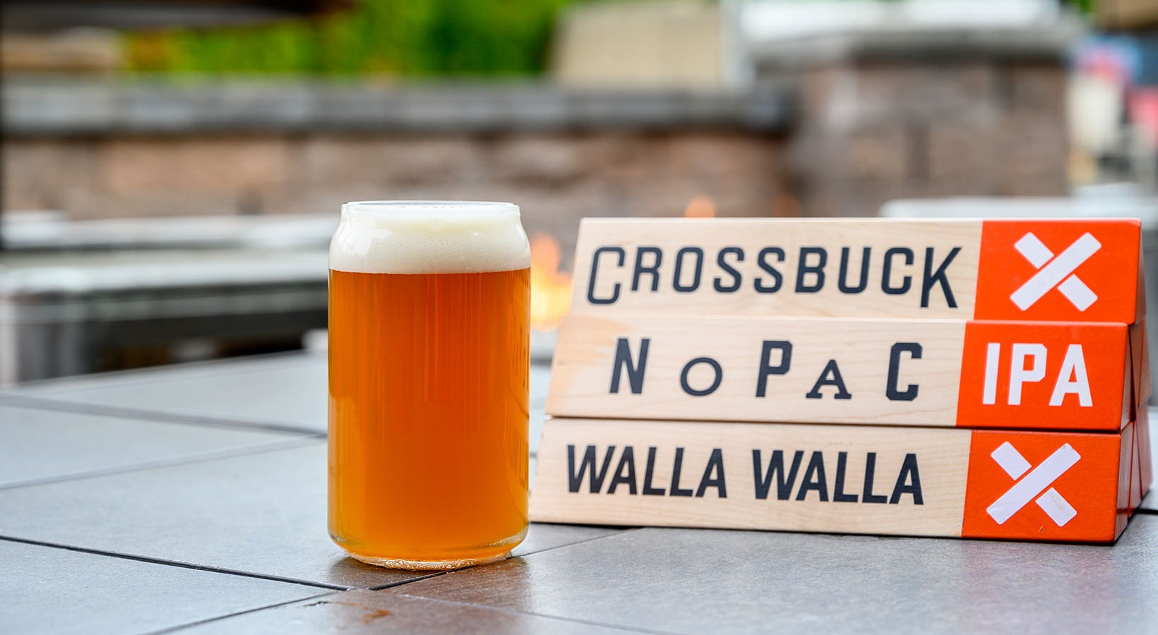 Crossbuck Brewing beer in a clear glass with Crossbuck sign